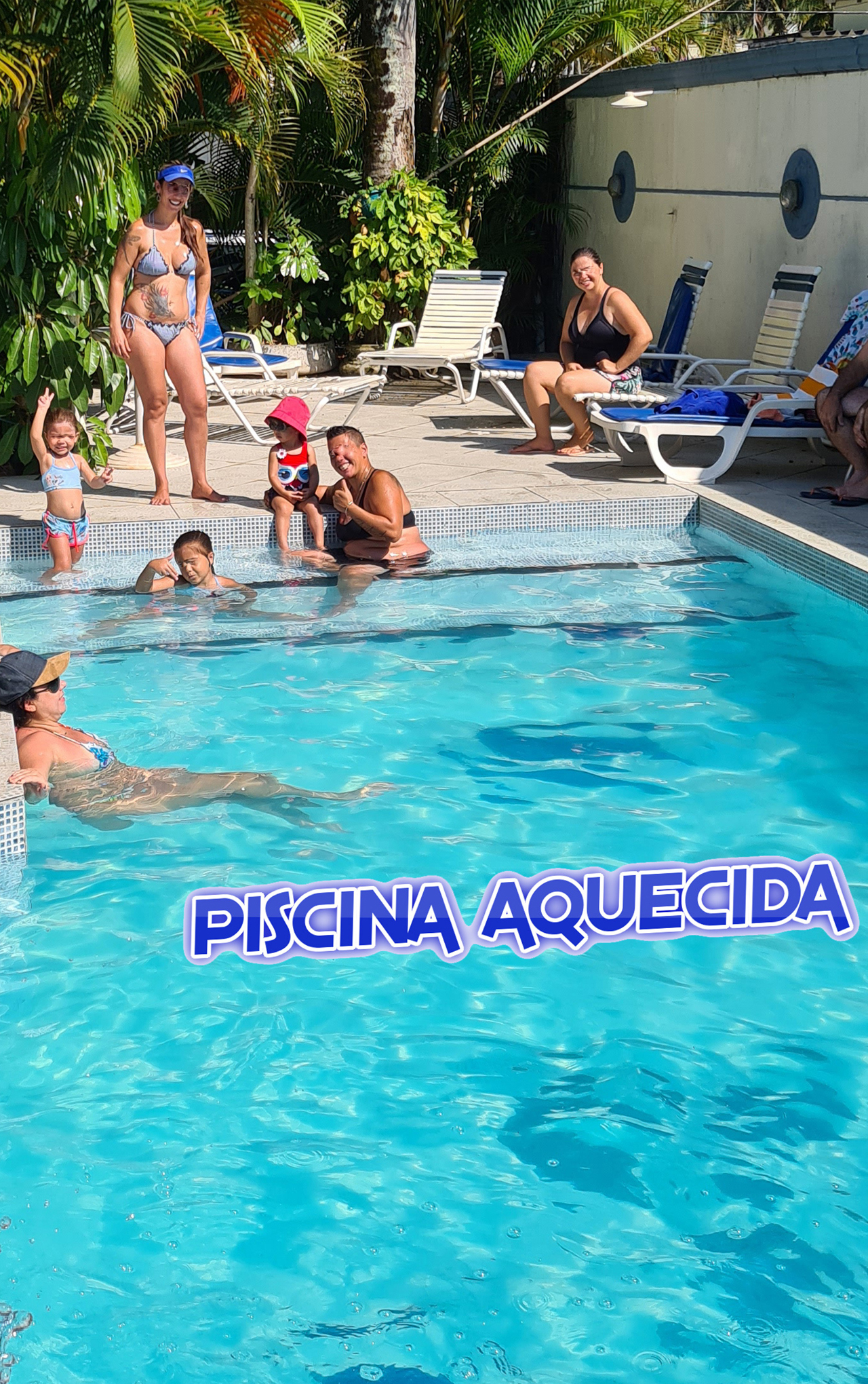 Famílias e crianças na piscina aquecida, curtindo a mesma e o sol